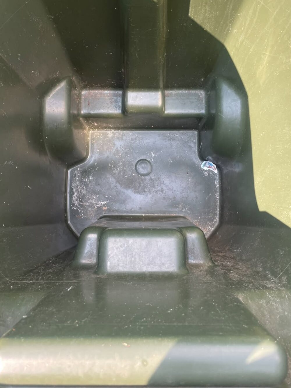 The inside of a wheelie bin, black with caked-on grime before cleaning