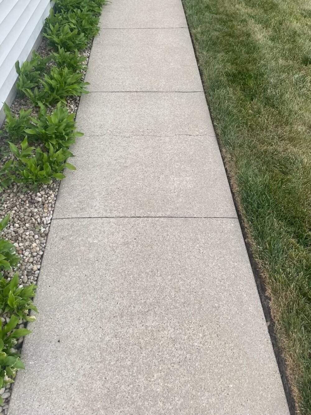 The same side sidewalk cleaned to a pale even concrete finish