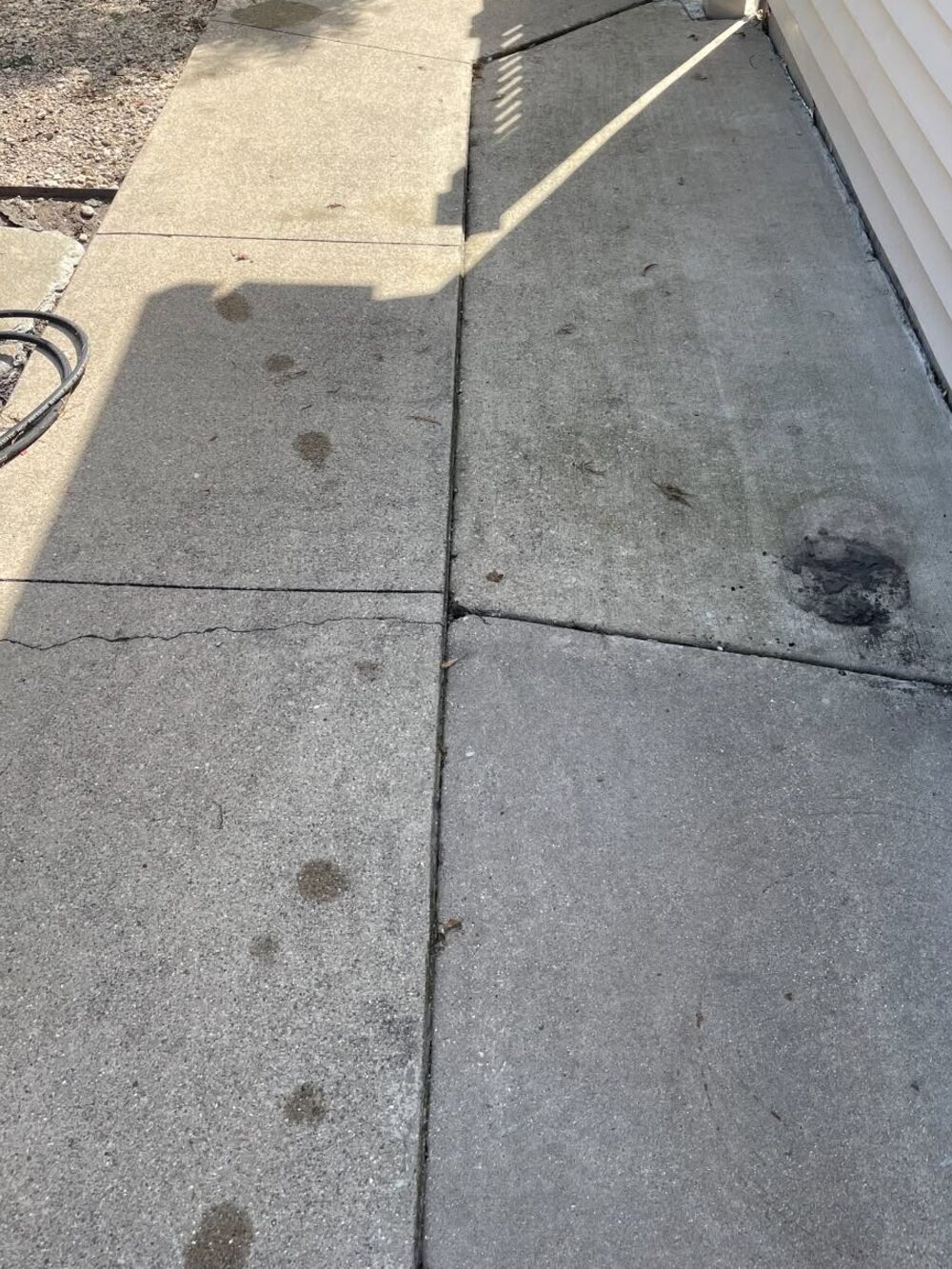 A narrow side patio with stained and spotted concrete before cleaning